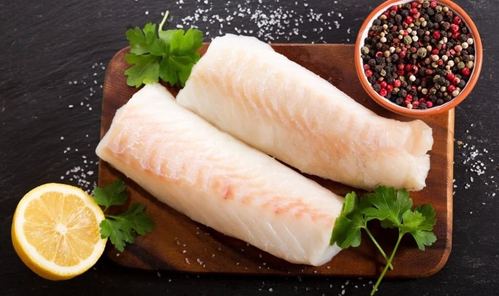 Dos filetes de bacalao crudo, destacando la carne blanca pálida y su potencial para la preparación culinaria