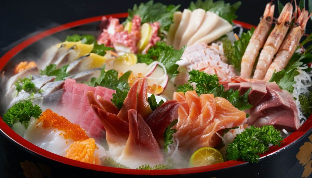 Un cuenco lleno de hielo, coronado con un colorido surtido de rodajas de sashimi fresco, incluyendo varios tipos de pescado